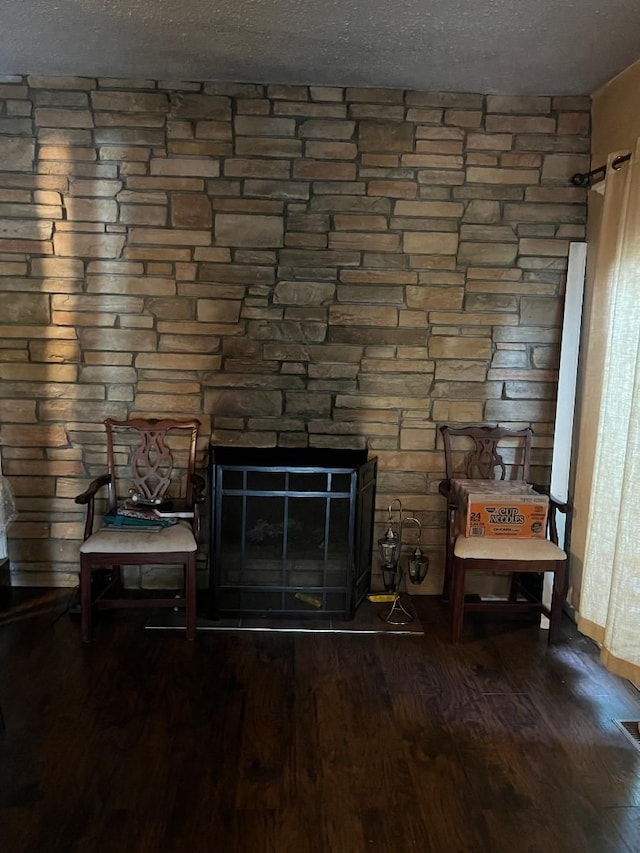 room details with a stone fireplace, wood-type flooring, and a textured ceiling