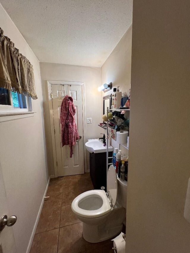 bathroom with tile patterned floors, vanity, a textured ceiling, and toilet