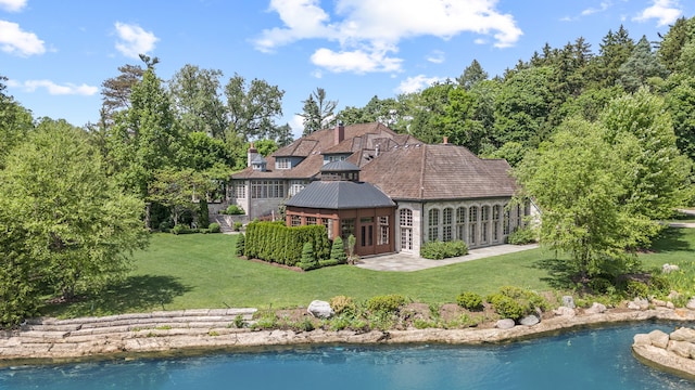 back of property featuring a lawn, a water view, and french doors