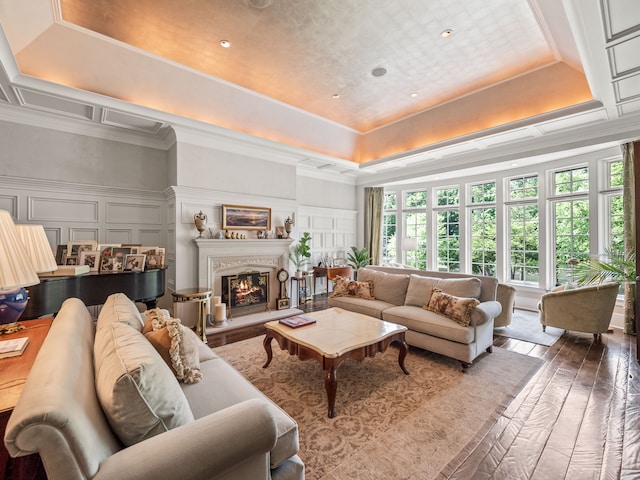 living room featuring a raised ceiling, ornamental molding, and hardwood / wood-style flooring