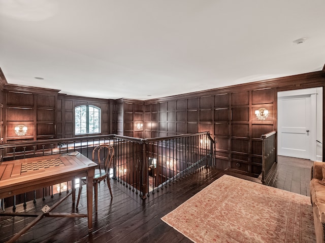 hallway with dark hardwood / wood-style floors, ornamental molding, and wood walls