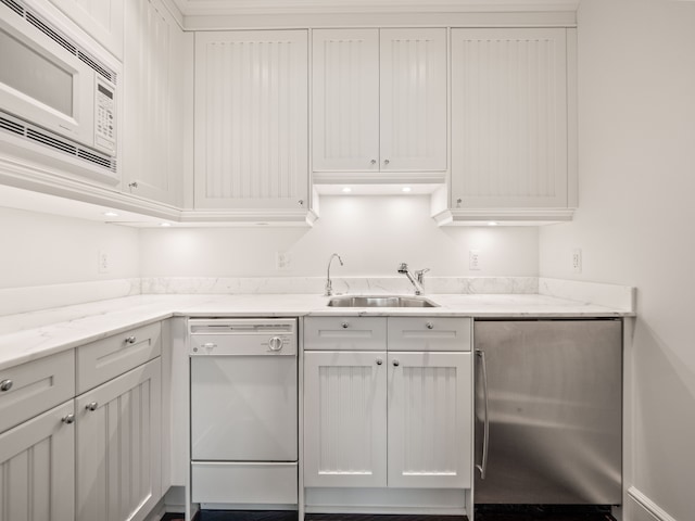 kitchen featuring white cabinets, white appliances, light stone countertops, and sink