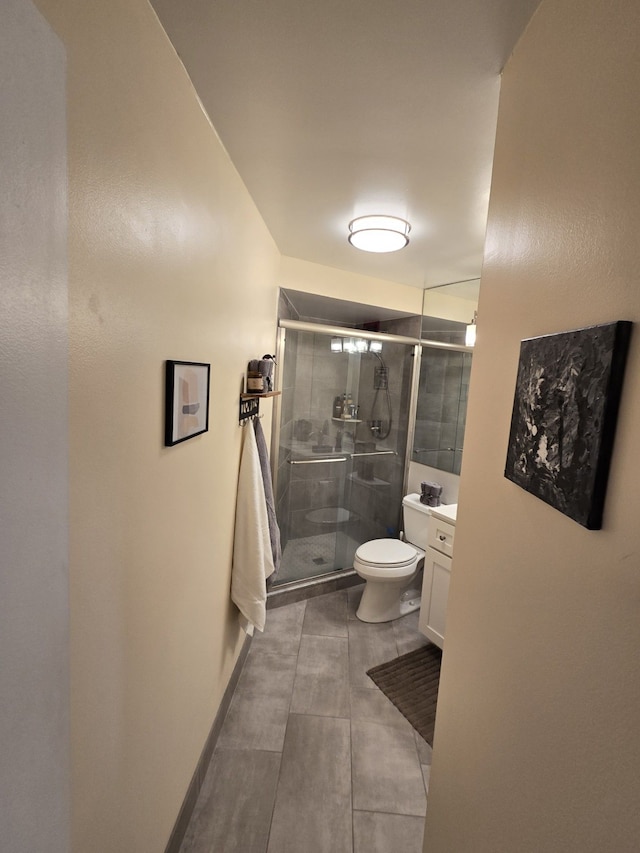 bathroom featuring tile patterned floors, vanity, toilet, and a shower with door