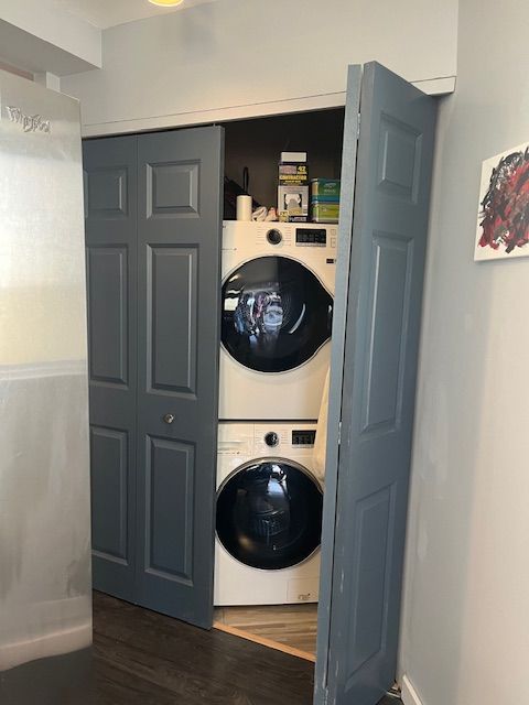 washroom with dark hardwood / wood-style flooring and stacked washing maching and dryer