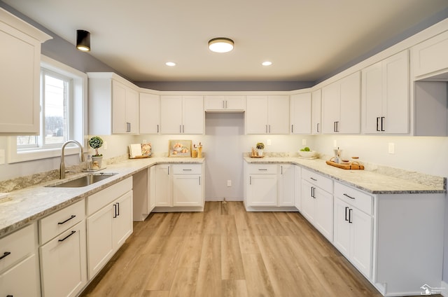 kitchen featuring light stone counters, sink, white cabinets, and light wood-type flooring