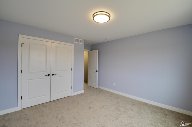 unfurnished bedroom featuring light colored carpet and a closet