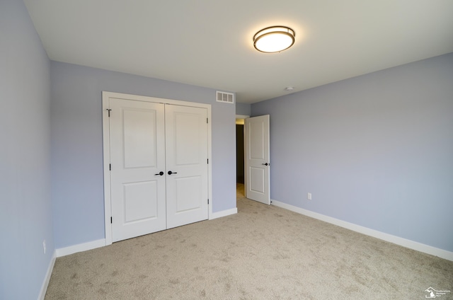 unfurnished bedroom featuring light colored carpet and a closet