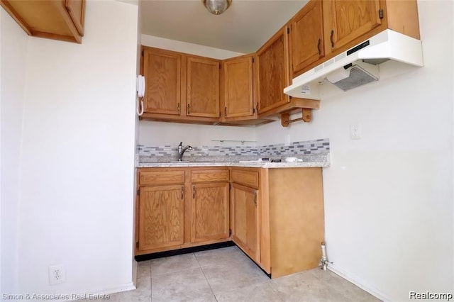 2439 Stieber St, Westland, MI 48186 - kitchen featuring under cabinet range hood, light countertops, light tile patterned floors, tasteful backsplash, and brown cabinetry