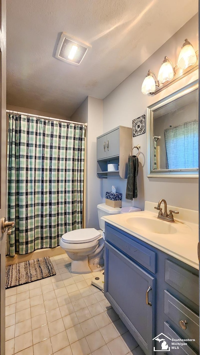 bathroom with tile patterned floors, vanity, toilet, and a textured ceiling