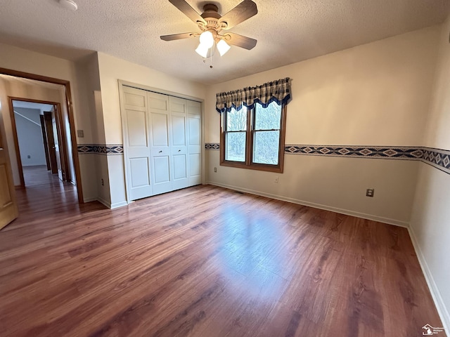 unfurnished bedroom with ceiling fan, wood-type flooring, a textured ceiling, and a closet