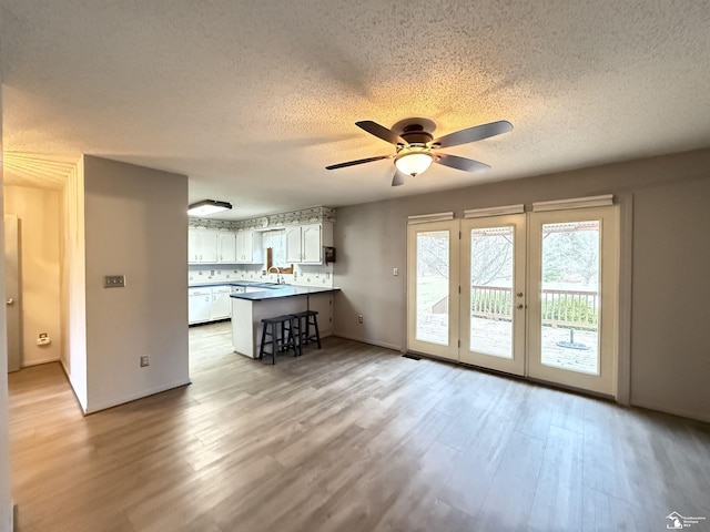 interior space with french doors, light wood-type flooring, a textured ceiling, ceiling fan, and sink