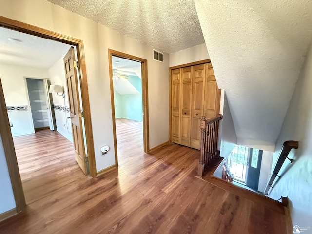 corridor with wood-type flooring and a textured ceiling