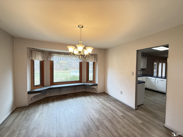 unfurnished dining area featuring a chandelier and hardwood / wood-style flooring