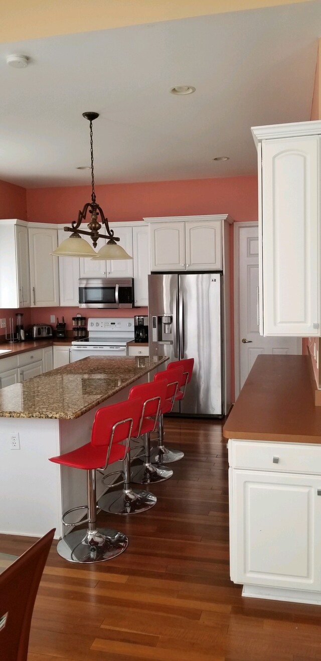 48280 Elmwood Dr, Shelby Twp, MI 48315 - kitchen featuring appliances with stainless steel finishes, dark wood-style flooring, white cabinets, pendant lighting, and dark stone countertops