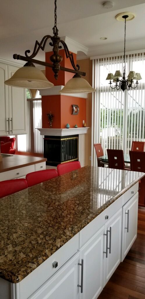 48280 Elmwood Dr, Shelby Twp, MI 48315 - kitchen featuring a chandelier, dark wood-style floors, white cabinets, a glass covered fireplace, and dark stone counters