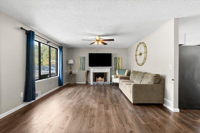 25217 King Rd, Romulus, MI 48174 - living room featuring a ceiling fan, a lit fireplace, dark wood-style flooring, a textured ceiling, and baseboards