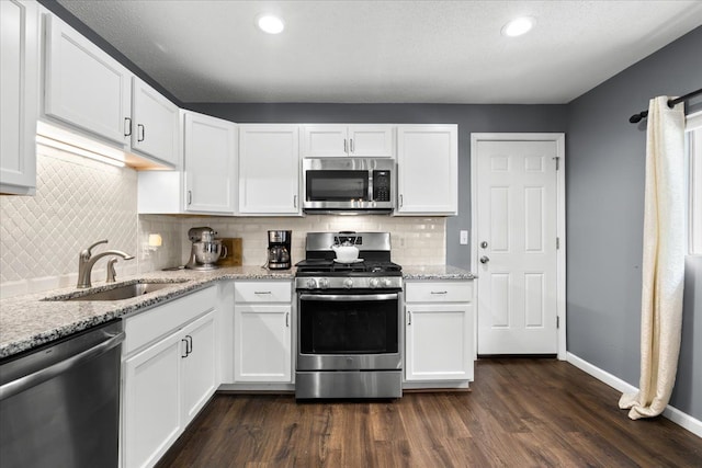 kitchen featuring dark hardwood / wood-style flooring, white cabinetry, light stone counters, and appliances with stainless steel finishes