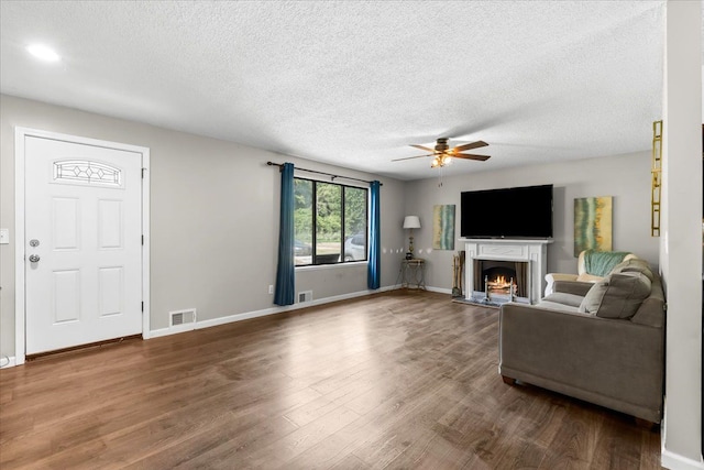 living room featuring ceiling fan, wood-type flooring, and a textured ceiling