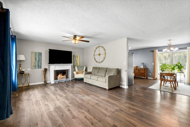 living room with ceiling fan with notable chandelier, dark hardwood / wood-style flooring, and a textured ceiling