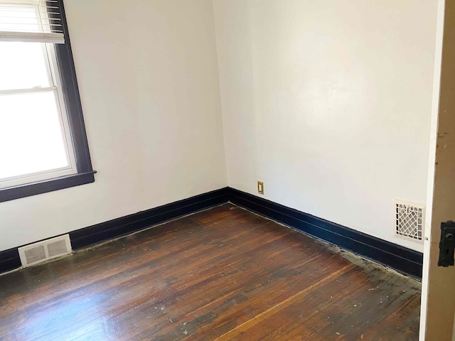 spare room featuring a healthy amount of sunlight and dark hardwood / wood-style flooring