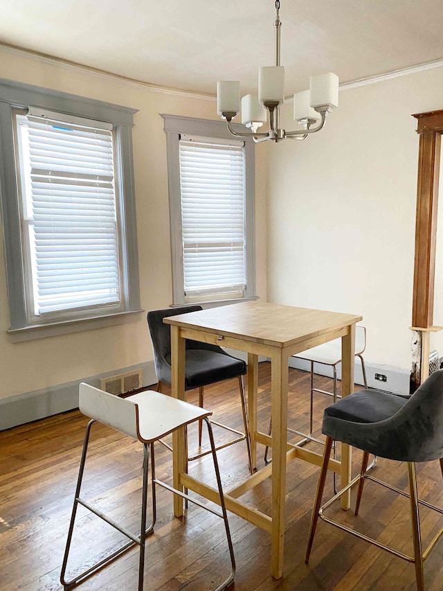 dining area with hardwood / wood-style floors, a notable chandelier, ornamental molding, and a wealth of natural light