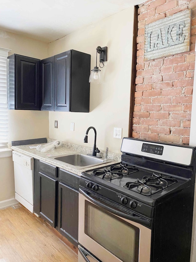 kitchen featuring light stone countertops, sink, range with gas cooktop, white dishwasher, and light wood-type flooring