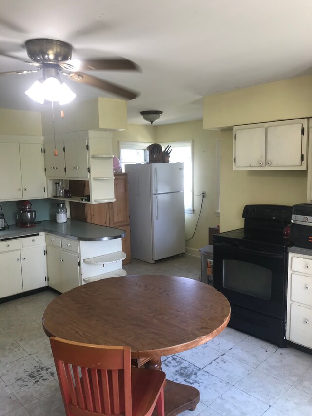 8620 Scio Church Rd, Ann Arbor, MI 48103 - kitchen with freestanding refrigerator, black range with electric cooktop, dark countertops, ceiling fan, and white cabinets