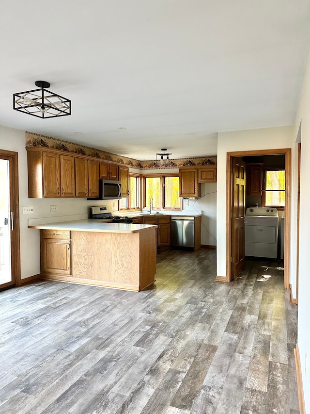 kitchen with kitchen peninsula, a wealth of natural light, stainless steel appliances, and washer / dryer