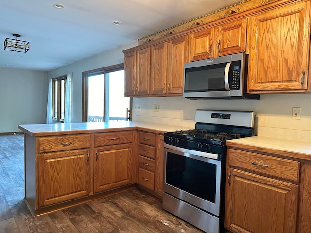 kitchen featuring kitchen peninsula, appliances with stainless steel finishes, and dark hardwood / wood-style flooring