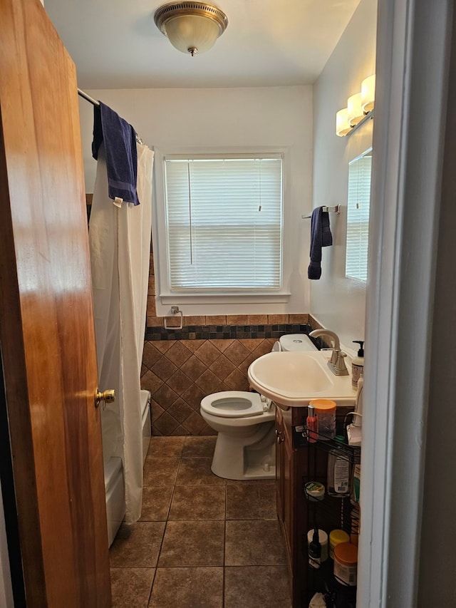 full bathroom with vanity, shower / bath combination with curtain, tile patterned flooring, toilet, and tile walls