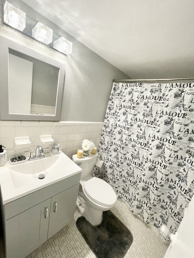 bathroom featuring tile patterned flooring, vanity, tile walls, and toilet