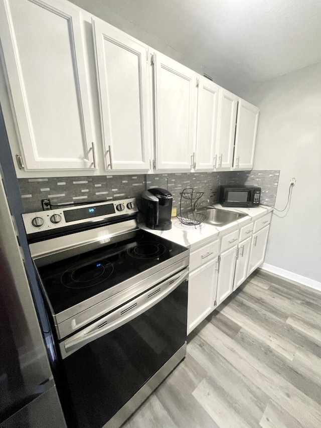 kitchen with white cabinetry, sink, tasteful backsplash, light hardwood / wood-style floors, and stainless steel range with electric stovetop