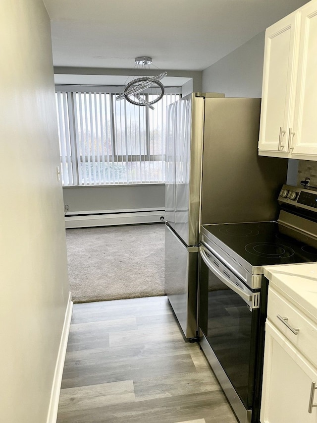 kitchen featuring a baseboard heating unit, stainless steel electric stove, white cabinets, light wood-type flooring, and a notable chandelier