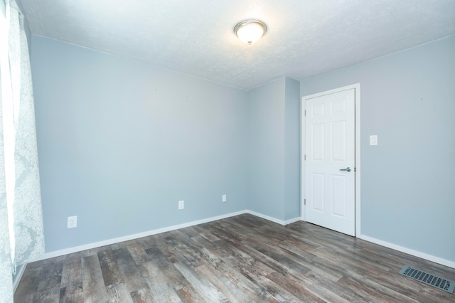 empty room featuring a textured ceiling and dark hardwood / wood-style floors