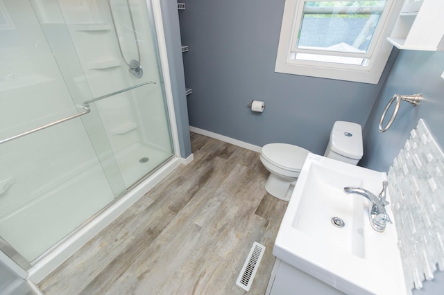 bathroom with hardwood / wood-style floors, vanity, toilet, and walk in shower