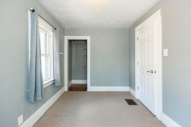 unfurnished bedroom featuring a textured ceiling, light colored carpet, and a closet