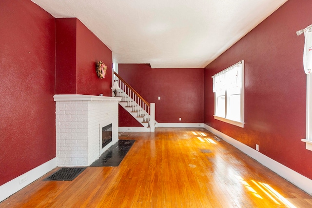 unfurnished living room with hardwood / wood-style floors and a brick fireplace