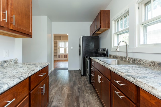 kitchen featuring dark hardwood / wood-style flooring, light stone counters, sink, radiator heating unit, and stainless steel electric range oven