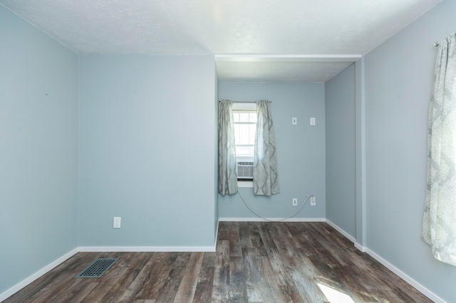 empty room with a textured ceiling, dark hardwood / wood-style flooring, and cooling unit