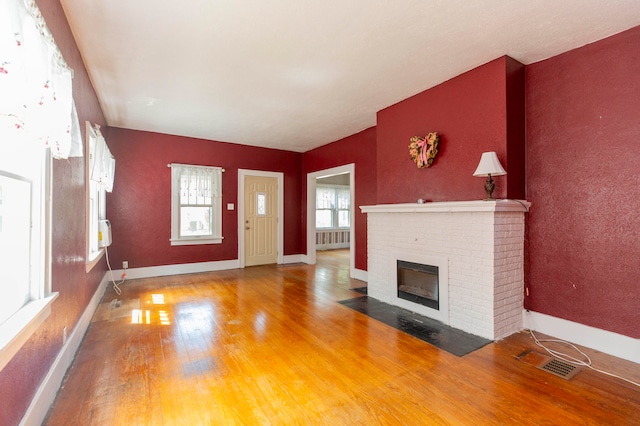 unfurnished living room with a fireplace, radiator heating unit, and hardwood / wood-style flooring