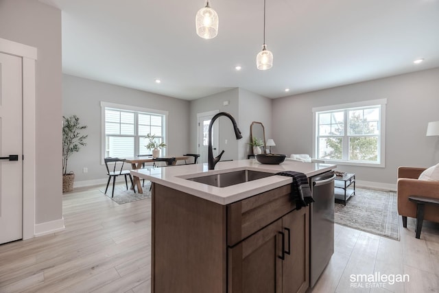 kitchen featuring a kitchen island with sink, decorative light fixtures, a wealth of natural light, and light hardwood / wood-style floors