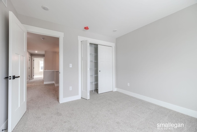 unfurnished bedroom with light colored carpet and a closet