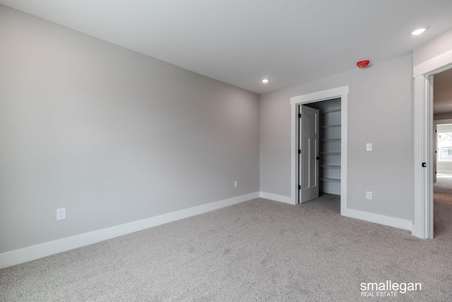 unfurnished bedroom with a walk in closet, light carpet, and a closet