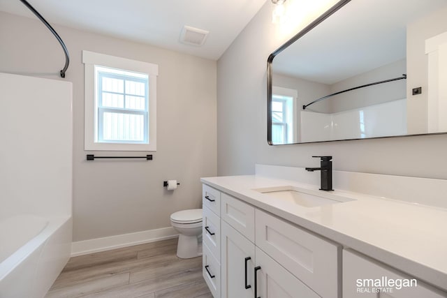 full bathroom featuring washtub / shower combination, wood-type flooring, toilet, and vanity