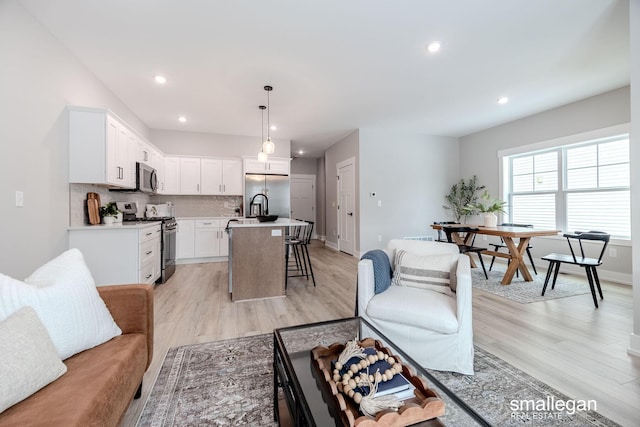 living room featuring light wood-style flooring, baseboards, and recessed lighting