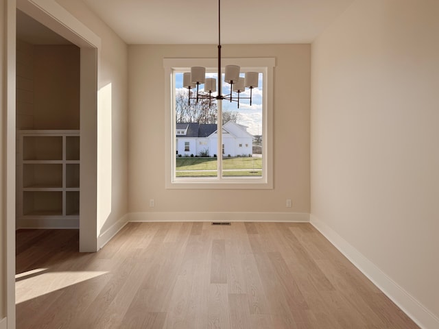 unfurnished dining area with light hardwood / wood-style floors and a notable chandelier