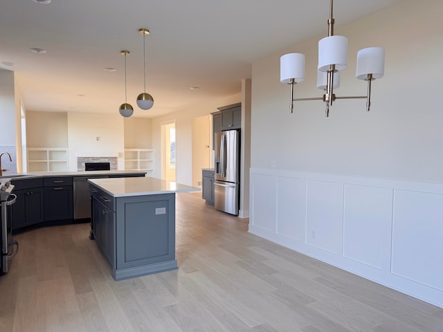 kitchen with decorative light fixtures, sink, a center island, and stainless steel appliances