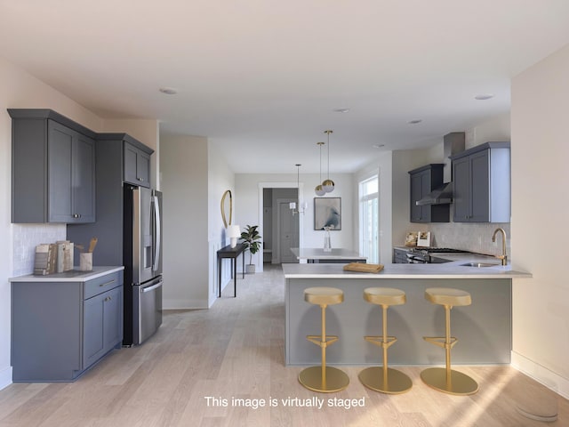 kitchen with kitchen peninsula, backsplash, stainless steel fridge with ice dispenser, and a kitchen breakfast bar