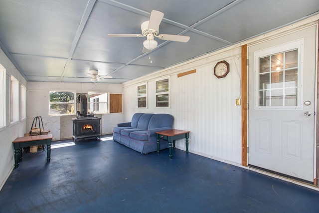 sunroom / solarium with a wood stove and ceiling fan