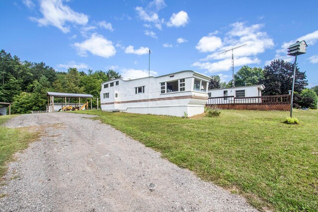 6662 Lorne Dr, Pentwater, MI 49449 - manufactured / mobile home with driveway, a front yard, a carport, and a deck
